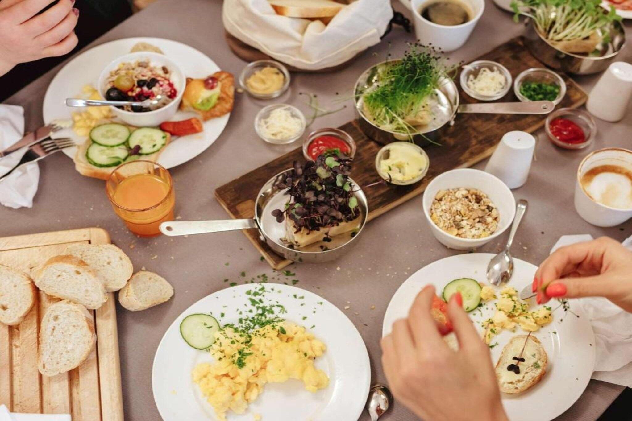 Uma mesa de jantar com diversos pratos, utensílios e acompanhamentos.