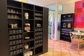 A modern interior with a large black shelving unit filled with various items, a small table with a chair, and a colorful wall. - Sunday Hotel Leipzig Südvorstadt (Markgraf) - Superior Double Room (Leipzig)