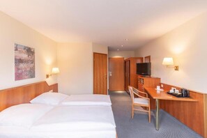 A hotel room with two beds, a desk with a chair, a television, and a painting on the wall. - Sunday Hotel Leipzig Südvorstadt (Markgraf) - Superior Double Room (Leipzig)