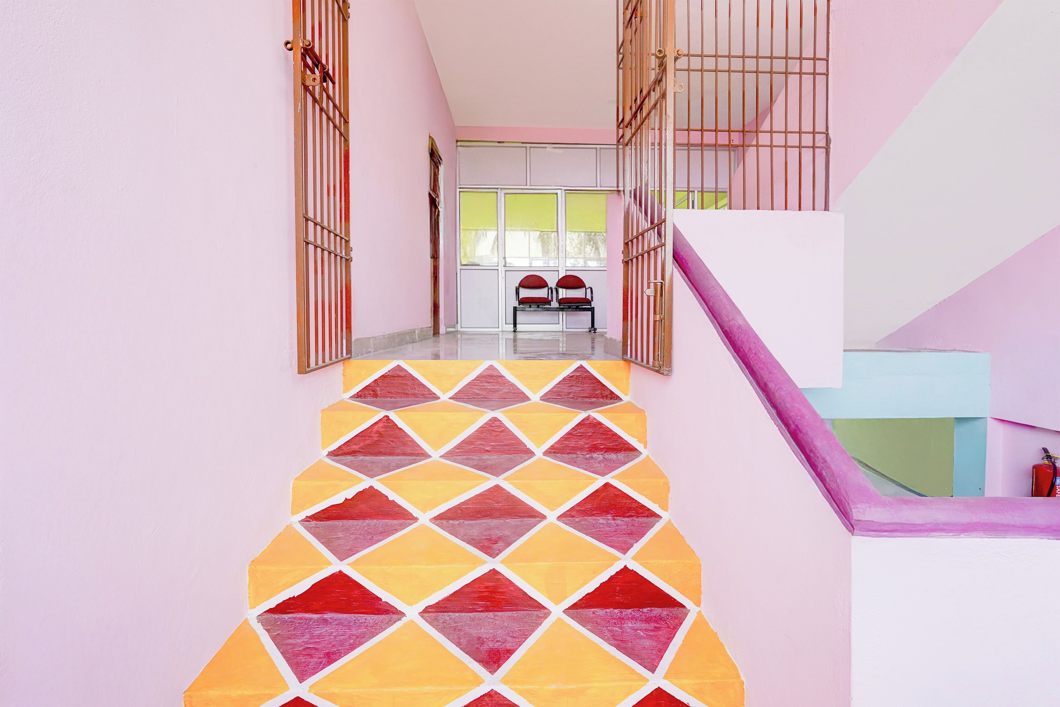 Uma escadaria com piso de padrão geométrico que leva a um quarto com janela e um banco.