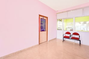 Een kamer met een deur waarop '9' staat, een bank met rode kussens en een raam met een geel vouwgordijn.