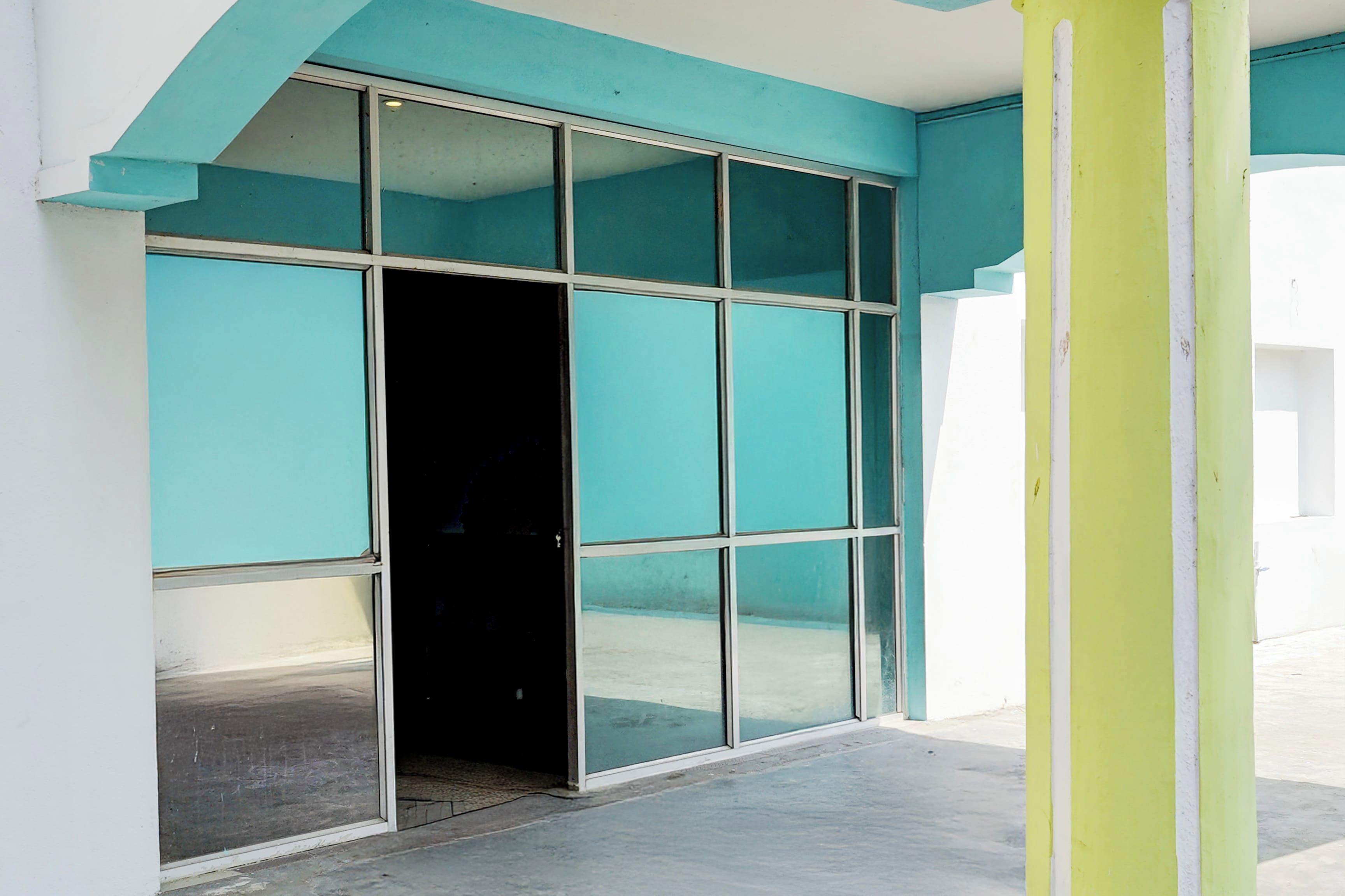 A building entrance with a glass door and teal-colored walls.