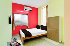 Una habitación con cama, armario, ventana con cortinas, equipo de aire acondicionado y bandeja con tazas y tetera.