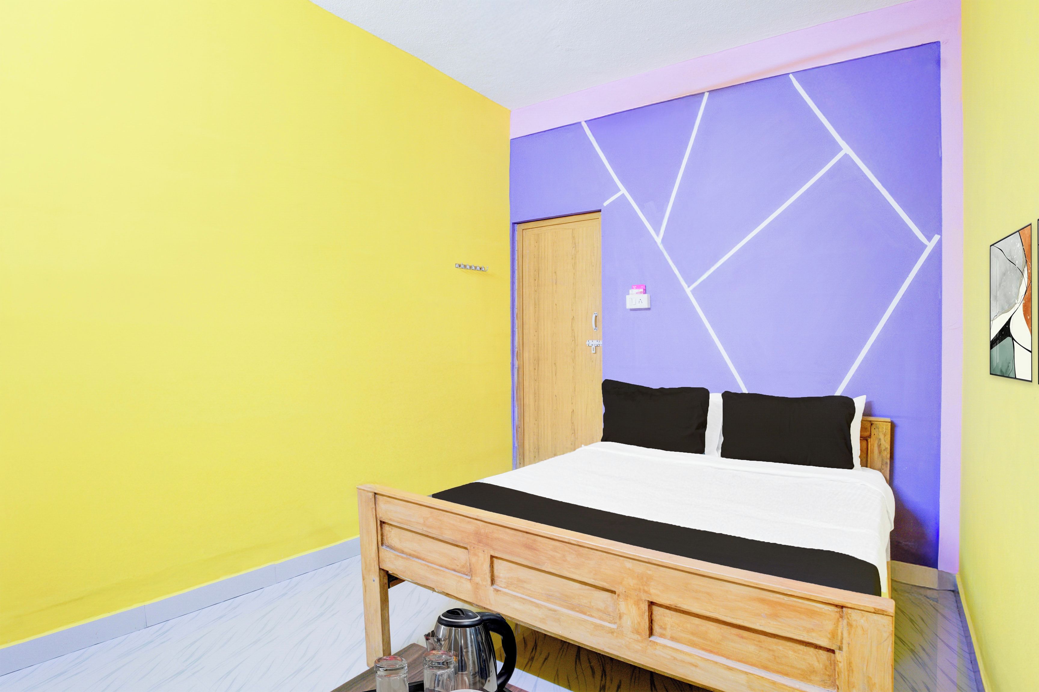 Quarto com cama, cabeceira de madeira, parede com padrões geométricos e uma porta.