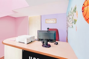 Un mostrador de recepción con un monitor de computadora, una impresora y un certificado enmarcado en la pared.