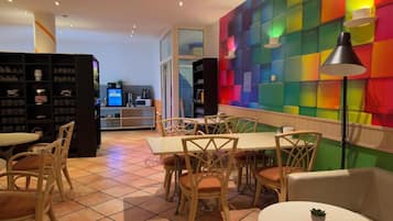 A restaurant with a colorful wall, wooden chairs, and a tiled floor.