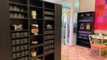 A modern interior with a large black shelving unit filled with various items, a small table with a chair, and a colorful wall.
