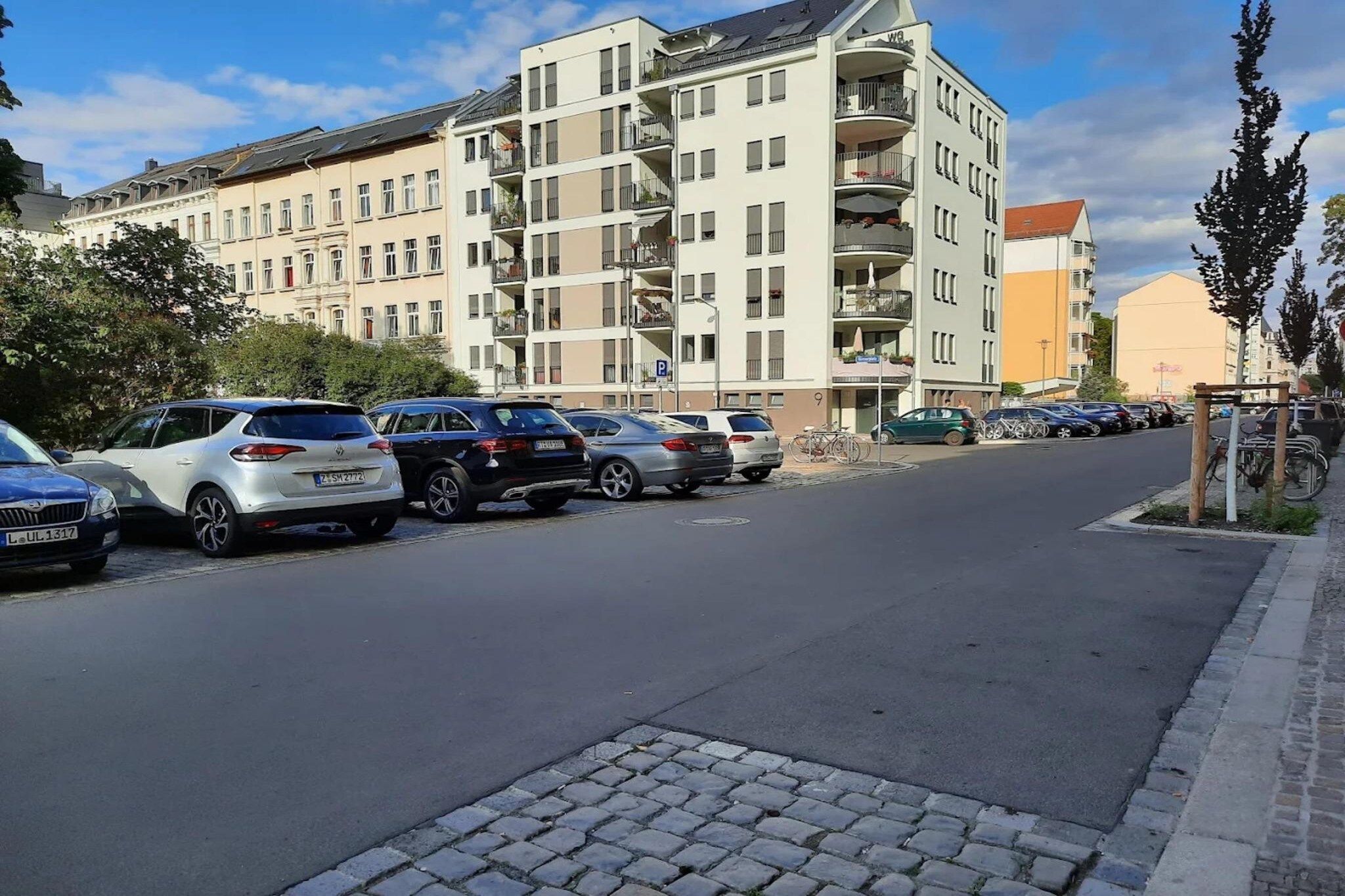 Ein mehrgeschossiges Wohngebäude mit Parkplatz davor.