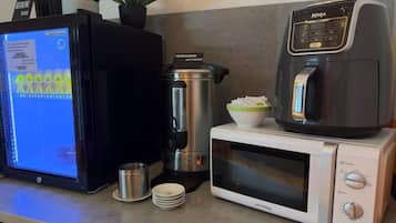 A kitchen with a coffee maker, a microwave, a kettle, and a computer monitor displaying a menu.