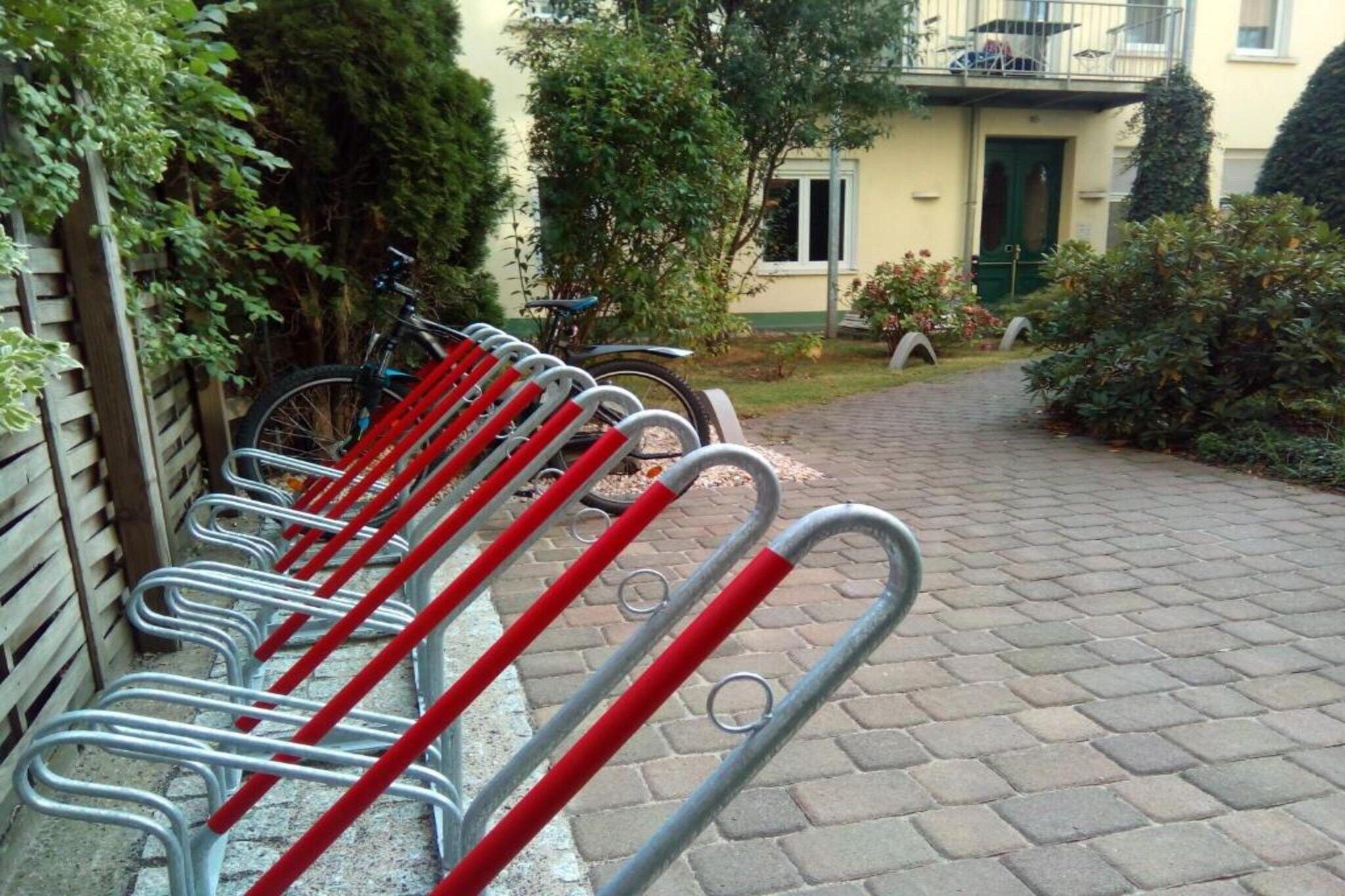 A row of bicycles parked on a paved path with a building in the background.