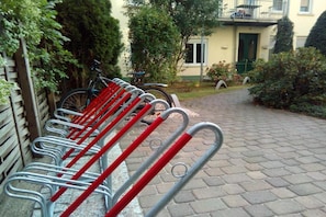 A row of bicycles parked on a paved path with a building in the background. - Sunday Hotel Leipzig Südvorstadt (Markgraf) - Budget Double Room (Leipzig)