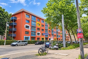 A multi-story building with balconies, a street sign, parked cars, and a pedestrian crossing sign. - Sunday Hotel Leipzig Südvorstadt (Markgraf) - Budget Double Room (Leipzig)