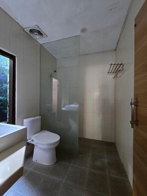 A bathroom with a toilet, a sink, and a shower area. - Hotel Ikhtiar Surya (Banyuwangi)