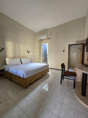 A hotel room with a bed, a chair, a desk, and a window. - Hotel Ikhtiar Surya (Banyuwangi)