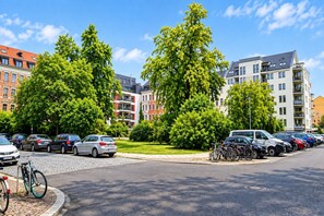 A parking area with cars and bicycles, surrounded by trees and buildings with multiple floors and balconies. - Sunday Hotel Leipzig Südvorstadt (Markgraf) - Comfort Double Room (Leipzig)