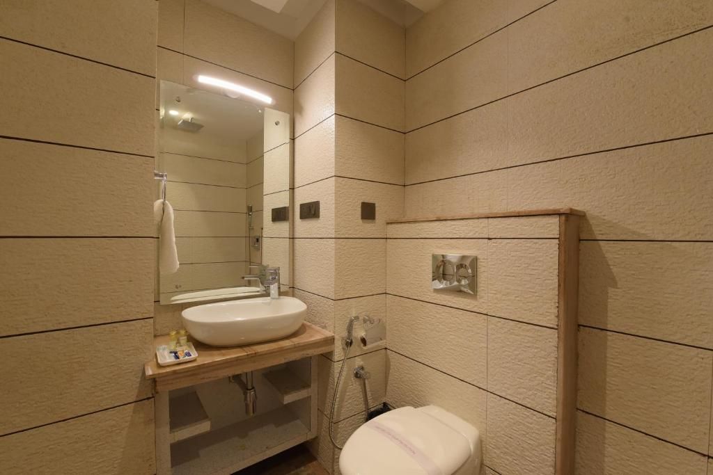 A bathroom with a sink, mirror, and toilet.