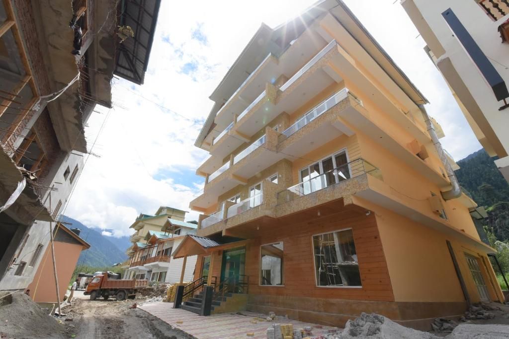 A multi-story residential building with balconies, a staircase, and a mountain backdrop.