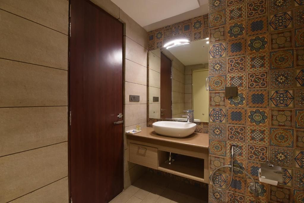 Un baño con puerta de madera, un lavabo blanco y un espejo.