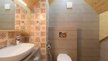 Un baño con un lavamanos grande, inodoro y zona de ducha.