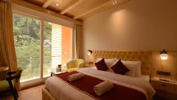 Habitación de hotel con una cama grande, una silla, una mesita de noche y vistas al exterior.