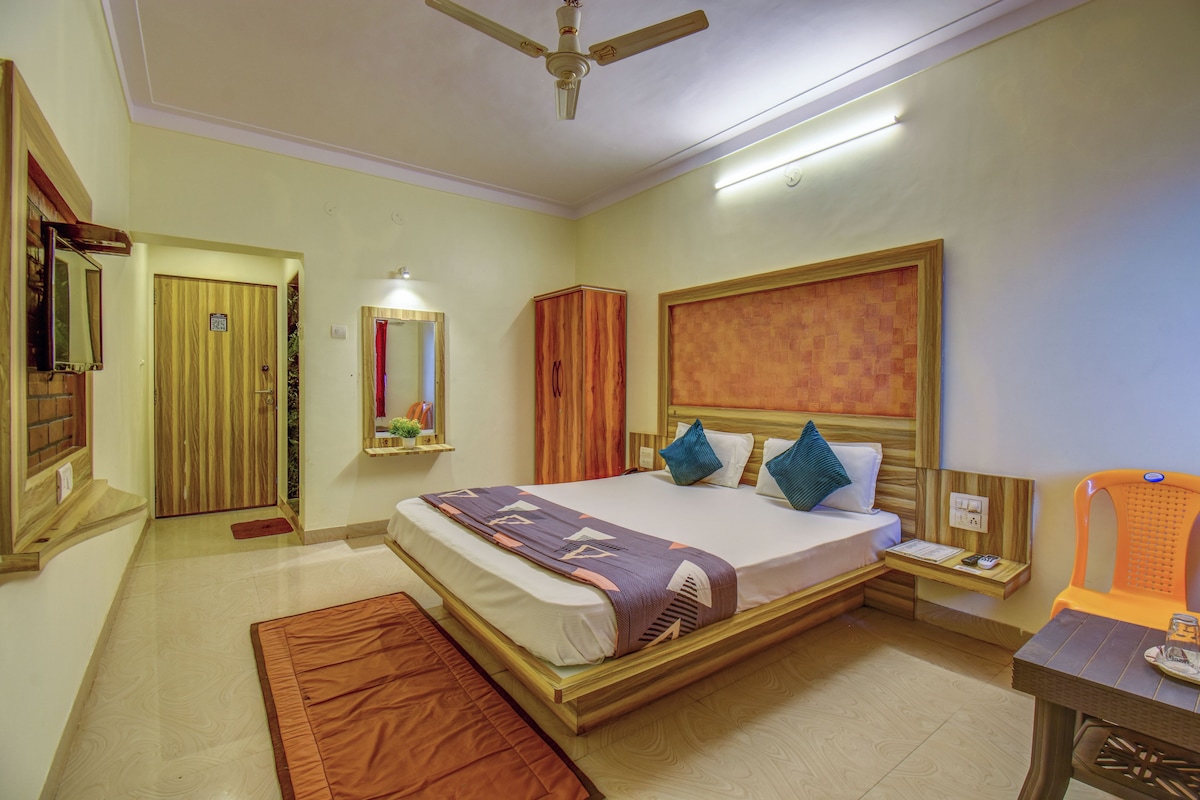 A hotel room with a bed, bedside table, nightstand, and a ceiling fan.