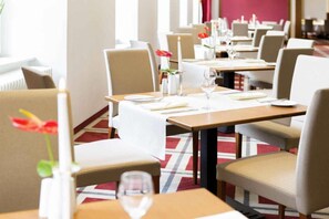 A hotel dining area with tables set for two, chairs, and a vase with a single flower. - Sunday Hotel Hildesheim Zentrum - Family room (Hildesheim)