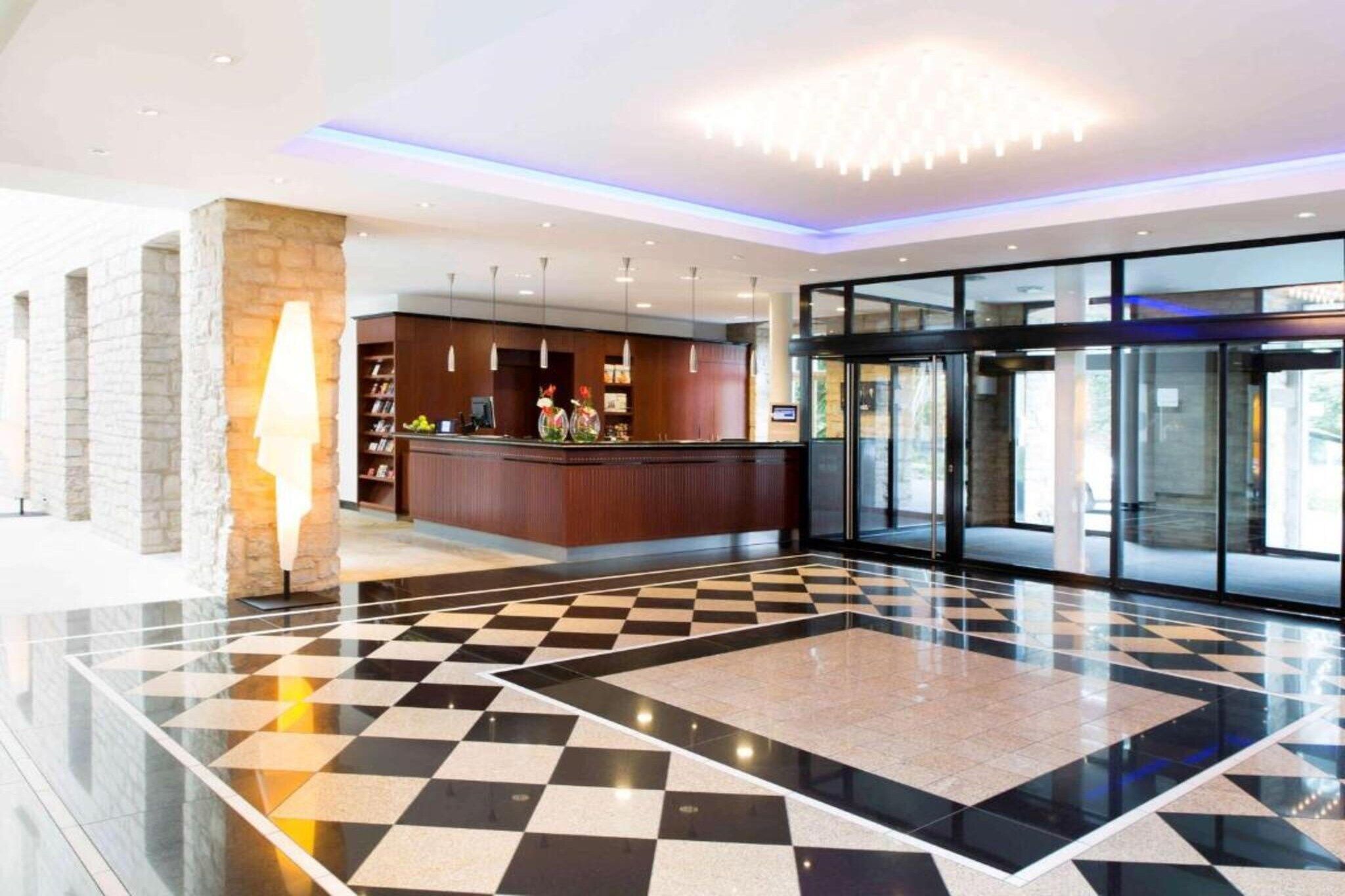 Vestíbulo de hotel con piso a cuadros, una recepción y una puerta giratoria.