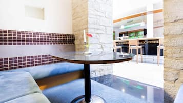 A modern lounge area with a round table, cushioned seating, and a decorative vase.
