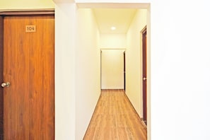 Un pasillo con piso de madera y una puerta con la leyenda '104'.