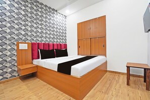 A bedroom with a wooden bed, a wardrobe, a bedside table, and a patterned wall.