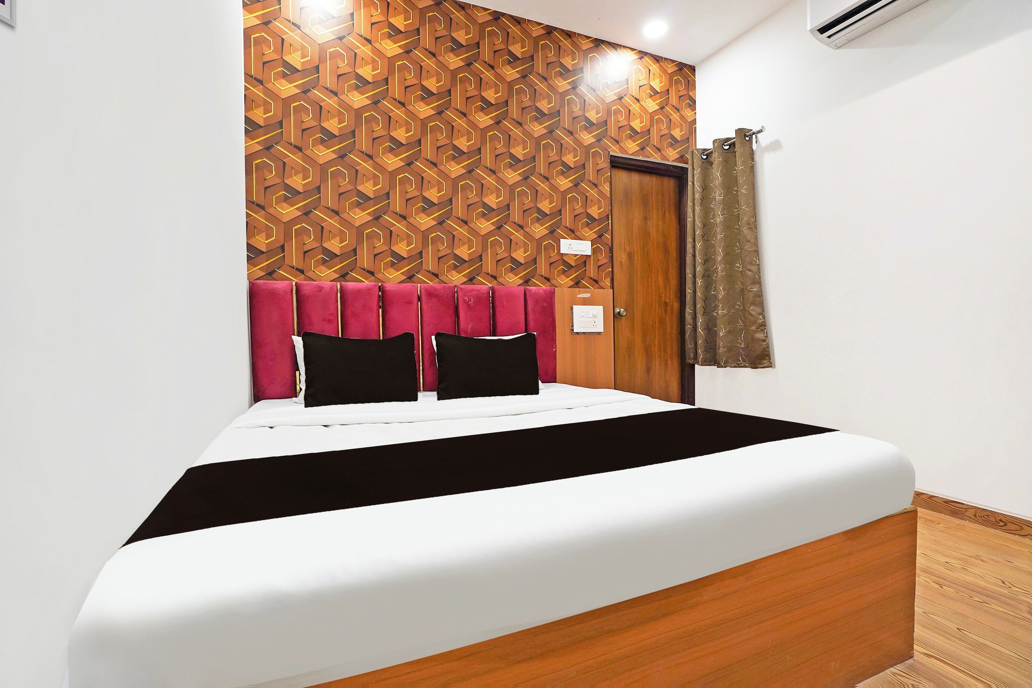 Una habitación de hotel con cama, cabecera de madera, pared con diseño y una cortina.