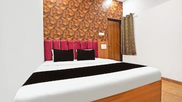 Una habitación de hotel con cama, cabecera de madera, pared con diseño y una cortina.