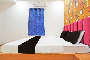 A hotel room with a bed, a blue curtain, a wall-mounted air conditioner, and a colorful mural.