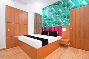 A bedroom with a bed, wooden wardrobe, and a wall with a geometric pattern. - Super Hotel O Sunshine Villa (Nagpur)