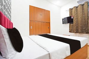 Una habitación de hotel con una cama, un armario, un televisor y una cortina.