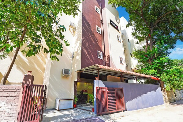 A building with a gated entrance, a covered outdoor area, and a visible air conditioning unit. - Super Hotel O Sunshine Villa (Nagpur)