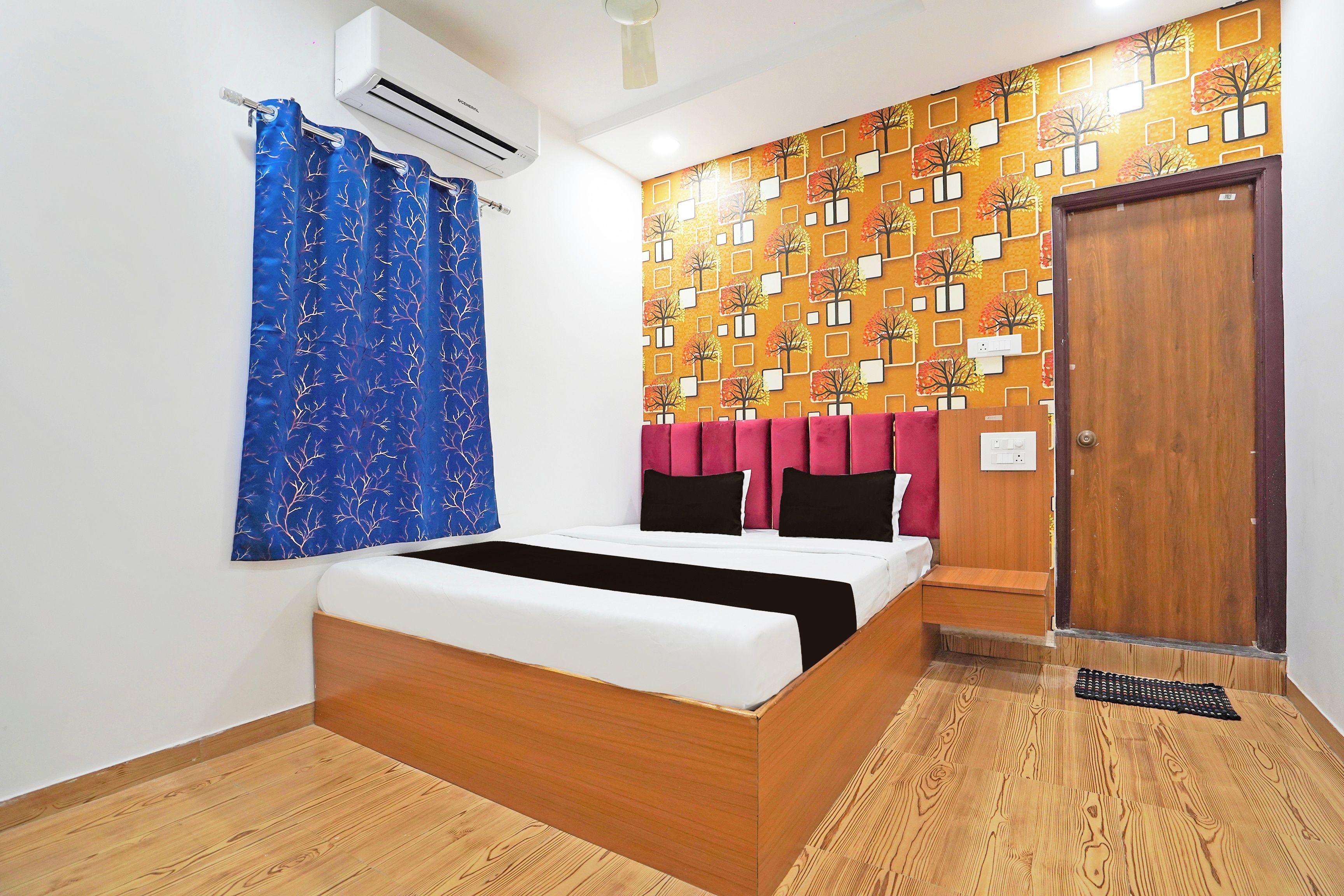 Un dormitorio con cama, aire acondicionado de pared, una puerta y pared con diseño.
