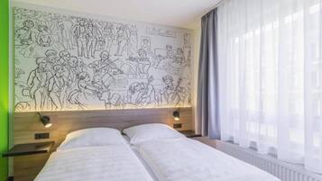 Ein Hotelzimmer mit einer großen Wandmalerei, einem Bett mit weißer Bettwäsche, einem Nachttisch und einem Fenster mit durchsichtigen Vorhängen.