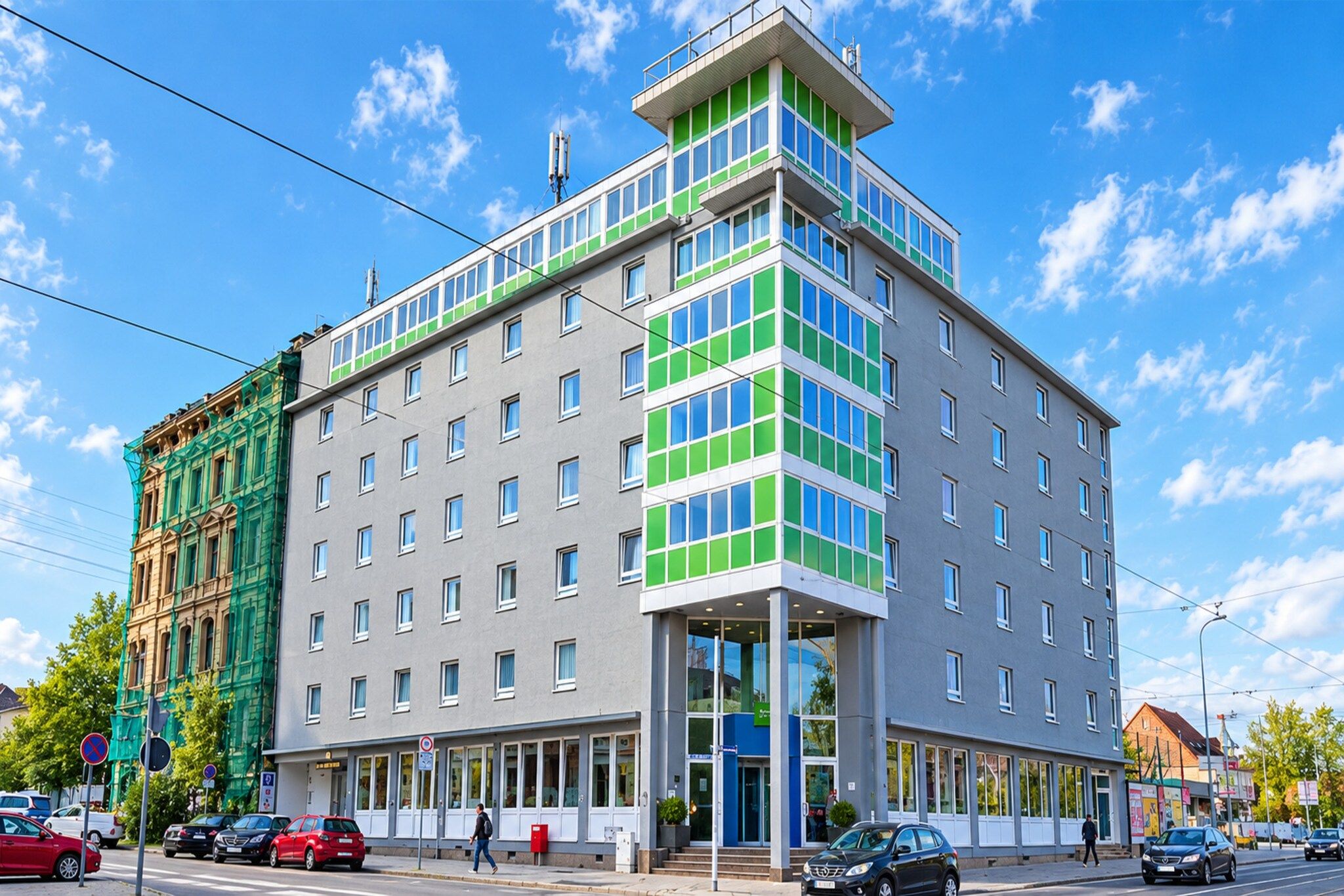 A multi-story hotel with a modern design, featuring a prominent corner entrance and a mix of window styles.