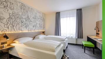 Ein Hotelzimmer mit zwei Betten, einem Schreibtisch, einem Stuhl, einer großen Wandmalerei und einem Fenster mit Vorhängen.