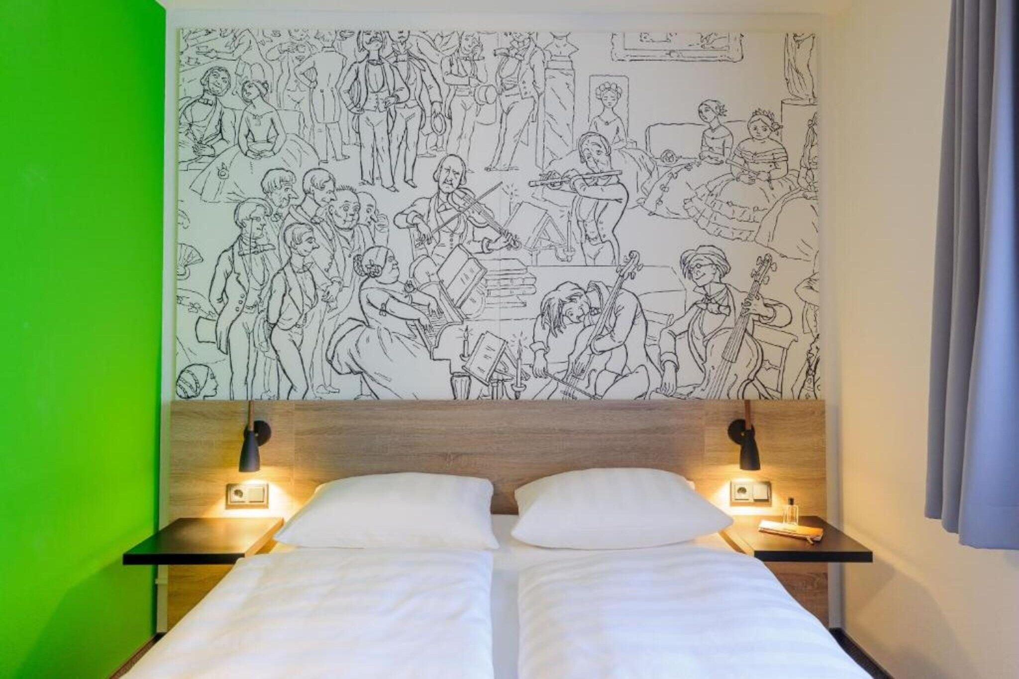 A hotel room with a large wall mural depicting a historical scene, two bedside tables with lamps, and a bed with white linens.