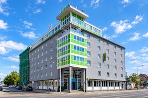 A multi-story hotel with a modern design, featuring a prominent green and white facade, large windows, and a ground-level entrance. - Sunday Hotel Halle Zentrum - Suite (Halle (Saale))