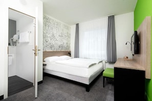 A hotel room with a bed, a desk, a mirror, a wall with a mural, and a bathroom visible through an open door. - Sunday Hotel Halle Zentrum - Suite (Halle (Saale))