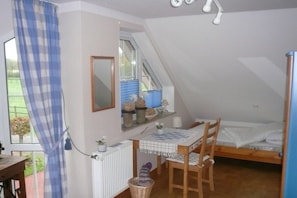 Une chambre de dortoir avec un lit superposé, un bureau avec une chaise, une fenêtre avec des rideaux et un radiateur.
