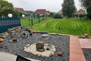 Un jardin avec un foyer, un espace salon et une pelouse clôturée.