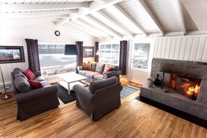 A living room with a fireplace, wooden flooring, and a sofa set.