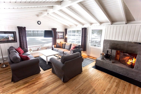 A living room with a fireplace, wooden flooring, and a sofa set.