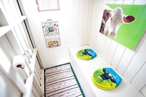 A narrow hallway with a wooden floor, a white door, and a wall-mounted puzzle rack.