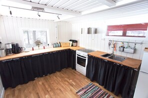 A compact kitchen with a wooden countertop, a stove, a sink, and a window.