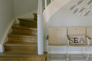 A wooden staircase with a white handrail and a white wall with a decorative fish pattern. - Holiday home in List with swimming pool (List)